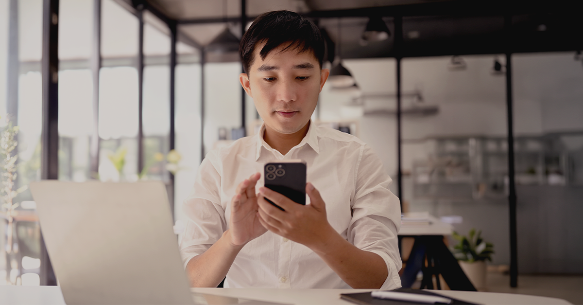 A person in professional clothing standing outdoors in an urban environment, holding a digital tablet.