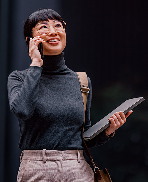 How AI-enabled BPaaS is managing complexity Person holding a tablet and speaking on a mobile phone outside a modern office building.